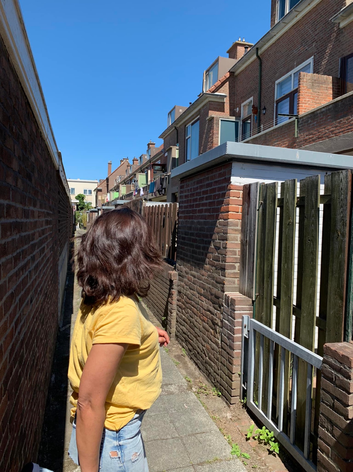 Een bewoonster kijkt omhoog naar de achterstallig onderhouden woningen in de Zeezwaluwstraat